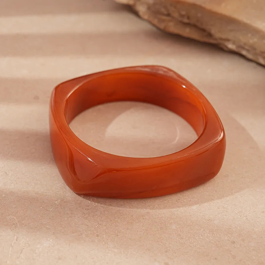 Amber resin stretch tile bracelet with gold elastic links on neutral surface