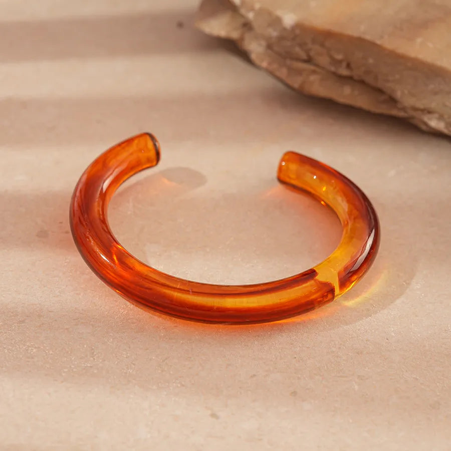 Amber resin bangles in modern shapes: geo, round, slim ring, open cuff and a stretch tile bracelet.