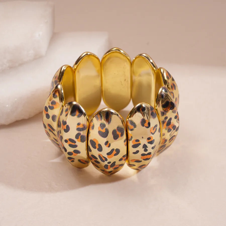 Leopard enamel oval stretch bangle with gold-tone edges stacked on wrist