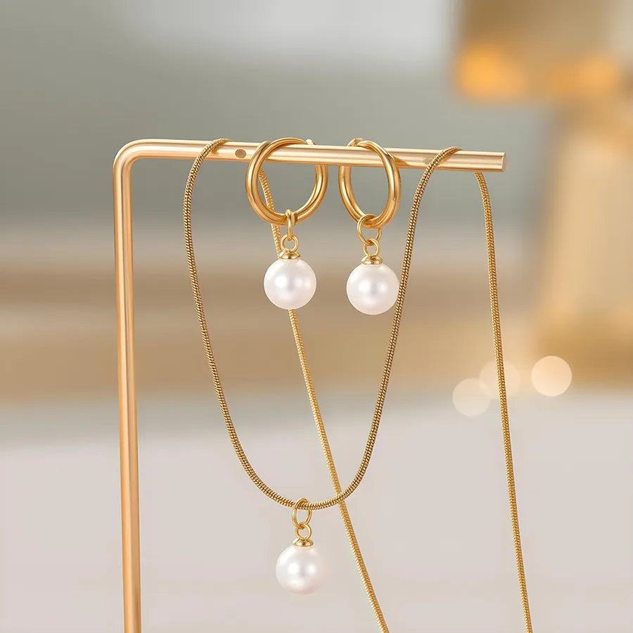Minimal gold-plated necklace and earrings set featuring round white pearls — modern elegant jewelry from The Layers.