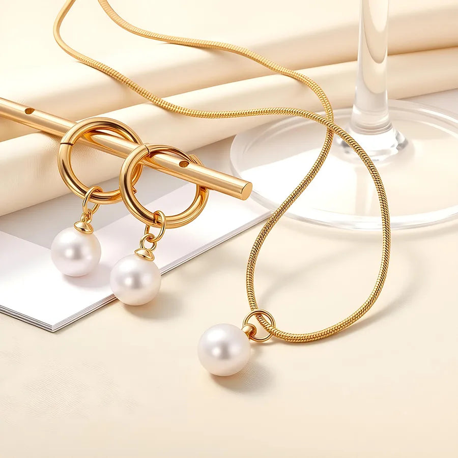 Minimal gold-plated necklace and earrings set featuring round white pearls — modern elegant jewelry from The Layers.