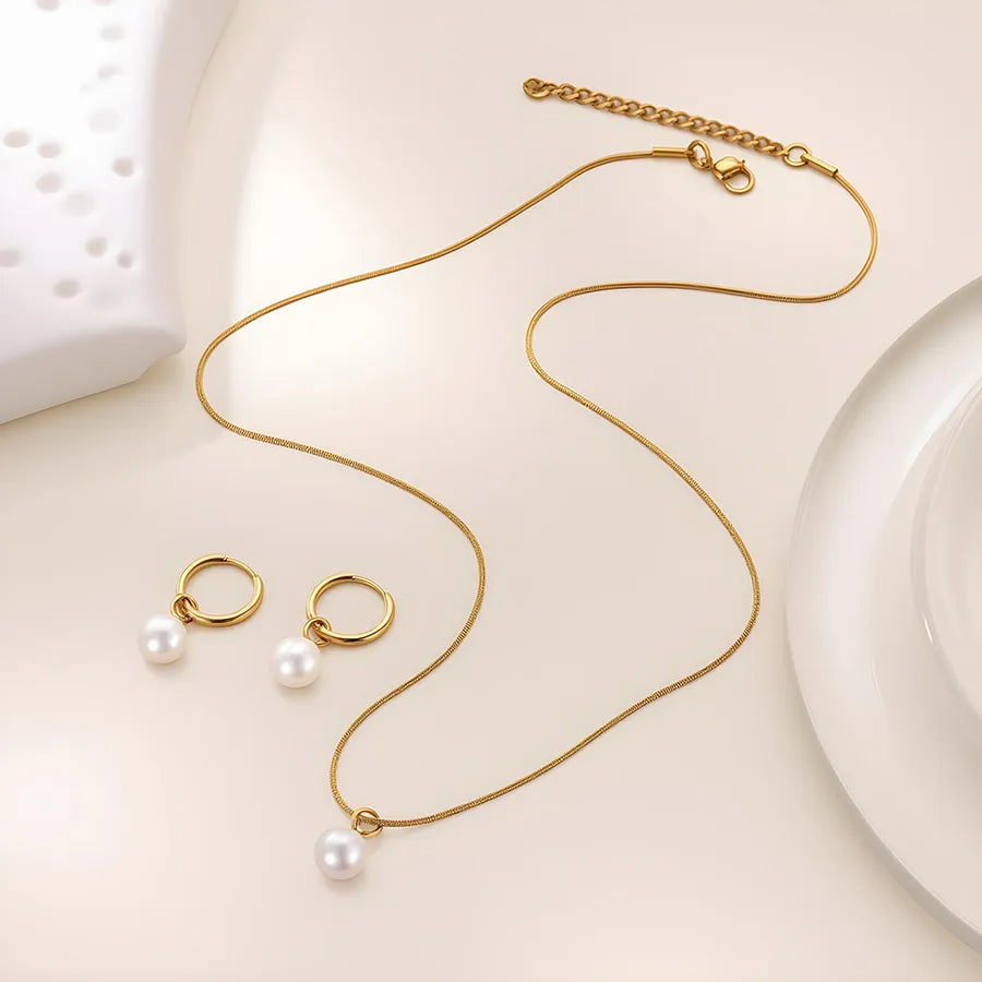Minimal gold-plated necklace and earrings set featuring round white pearls — modern elegant jewelry from The Layers.