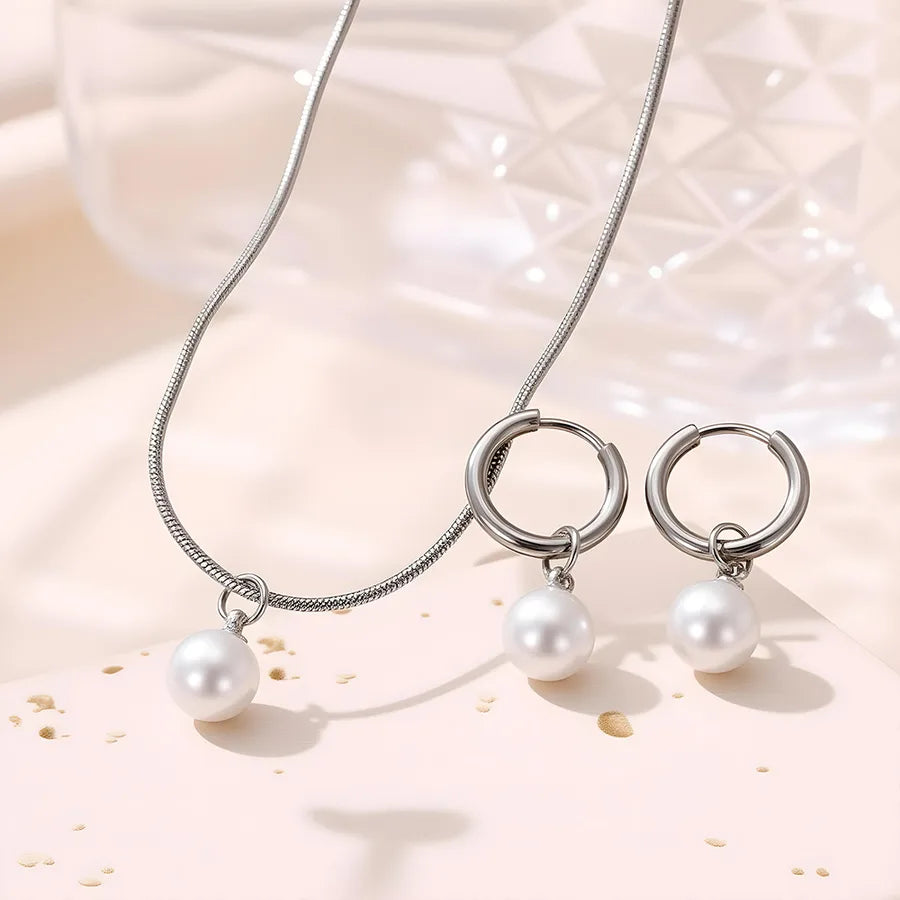 Minimal gold-plated necklace and earrings set featuring round white pearls — modern elegant jewelry from The Layers.