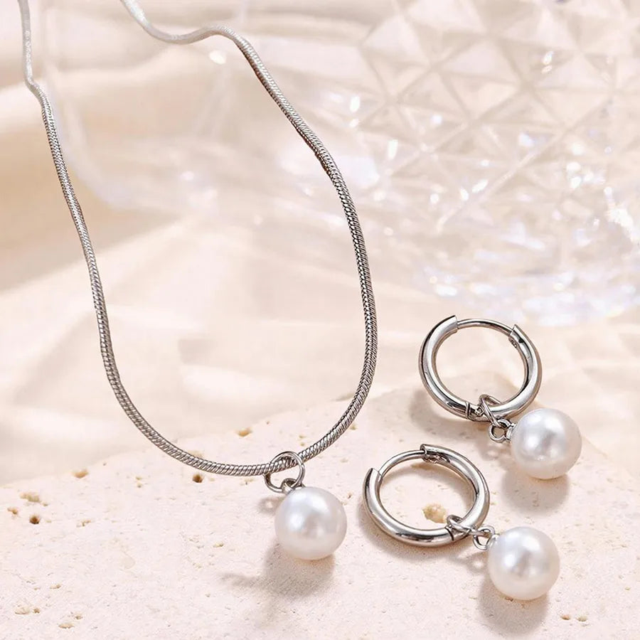 Minimal gold-plated necklace and earrings set featuring round white pearls — modern elegant jewelry from The Layers.